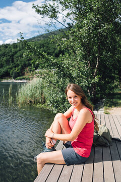 Smiling woman sitting on jetty by Lake Levico