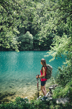 Young hiker with hiking poles looking at Lake Levico