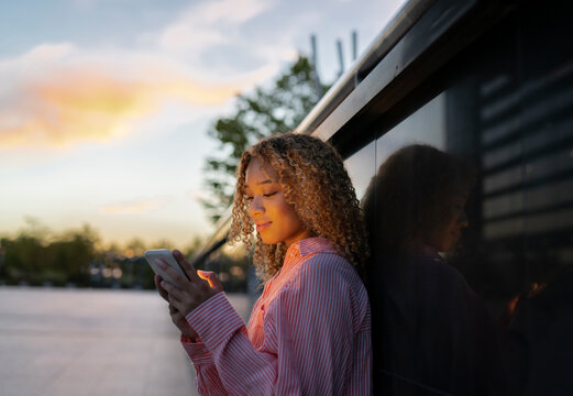 Woman using mobile phone in front of wall