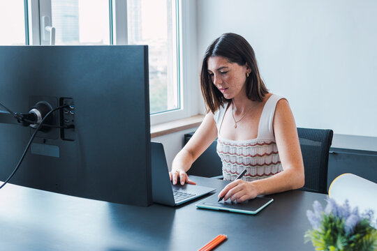 Smiling young graphic designer using laptop in office