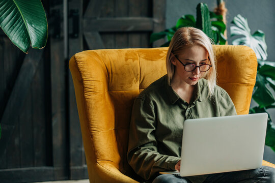 Businesswoman Using Laptop Sitting On Armchair At Home Office