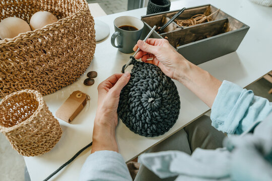 Hands of craftswoman crocheting at workbench