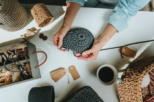 Hands of mature craftswoman crocheting at workbench