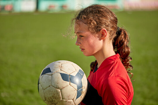 Thoughtful girl with soccer ball on sunny day