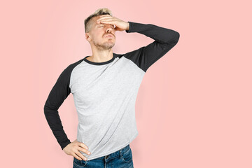 Portrait of young Caucasian man looking tired and exhausted and touching his forehead with hand....