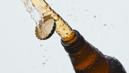 Cider splashing misted flask closeup. Cold lager beverage foaming fountaining