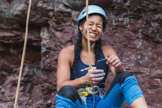 Happy strong rock climber on her phone