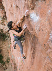 Focused woman jumping while rock climbing (dyno) - 2