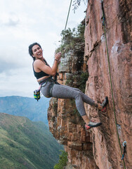 Passionate female rock climber hanging on cliff