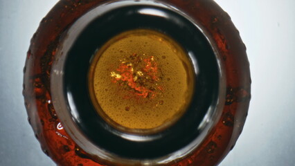 Bubbled craft swishing flask closeup. Overflowing beer waving splashing bottle