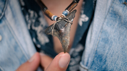 Fashionable man holding shark tooth necklace on tip of finger