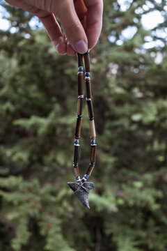 Fingers holding shark tooth necklace hanging