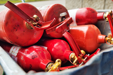 Many red fire extinguishers are lying in stack. Fire extinguishing equipment. Distribution of fire...