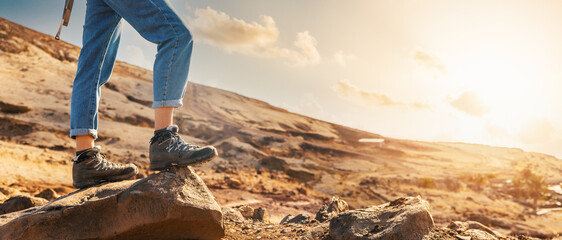 mountain trekking - woman hiker in hiking boots standing on rock. wild hike. banner with copy space