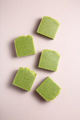 Handmade natural herbal green soap bars on dusty pink background