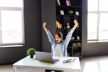 Yes. Happy excited woman at home workstation triumphing with raised hands