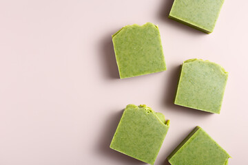 Handmade natural herbal green soap bars on dusty pink background