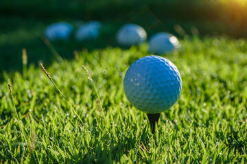 Golf ball is on tee at green lawn in a beautiful golf course with morning sunshine.Ready for golf in the first short.