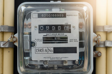 Front view of Power meter of Thailand attached to outdoor power pole. with yellow pipe beside of...