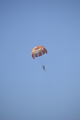 someone is trying a paragliding ride. Parasailing is a recreational activity when a person floats into the air by using a special parachute to be pulled by a vehicle
