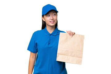 Young Asian woman taking a bag of takeaway food over isolated background thinking an idea while looking up