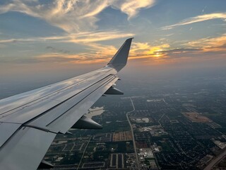 The wing of a commercial airline airplane while flying high in the sky over Dallas Texas on a trael vacation