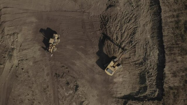 Bird eye view of tractor and excavator doing earthwork at construction site