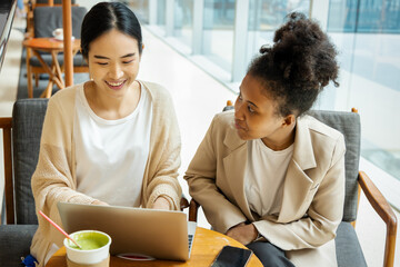 Teamwork between professional asian woman employee with African woman intern worker in working...