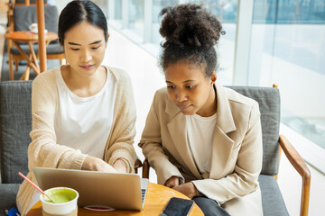 Serious and dedicated Asian and African worker working together in office building