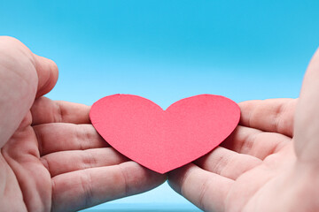 Fototapeta premium hands holding a red paper heart on a blue background. health care, hope, life insurance concept, world heart day, world health day, organ donor day, csr social responsibility, gratitude