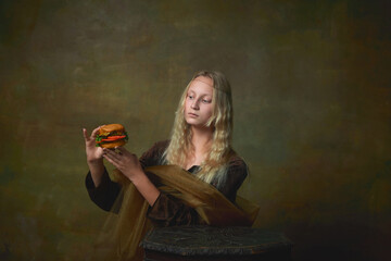 Strange thing. Vintage style portrait of young charming girl in image of Mona Lisa, La Gioconda looking at burger with surprise. Fast food, art, beauty, style, imitation
