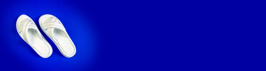 Women's summer white slippers on a blue background. Slippers. Banner for insertion into site. Place for text cope space.