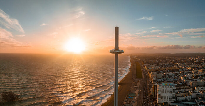 Magical sunset aerial view of British Airways i360 viewing tower pod with tourists in Brighton, UK with sea and Brighton Palace Pier in the background.
