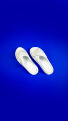 Women's summer white slippers on a blue background. Slippers. Vertical image