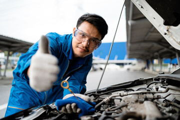 Smiling Asian mechanic in blue at garage, Asian mechanic fixing car in garage, car safety...