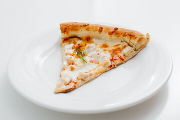 Close-up of one piece of cheese pizza on a white plate on the table