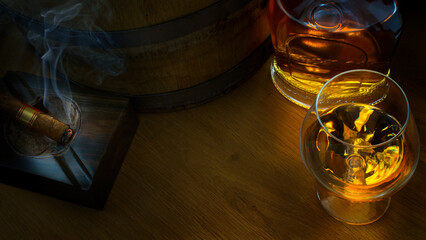 a glass of a luxurious alcoholic drink, an oak barrel, a bottle of cognac and a cigar on a dark...