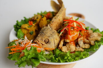 Fried gourami with salted egg sauce on wooden table, indonesian food nusantara, variety angle view