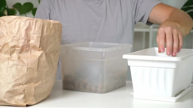 A man falls asleep in a flower box of expanded clay. Soil preparation, the first layer expanded clay. Preparation for planting plants. Gardening at home.