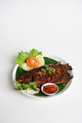 Grilled gourami or Gurame bakar with red barbeque sauce, vegetables, and chilli sauce