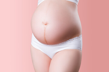 Linea nigra, pregnant woman in white panties on pink background
