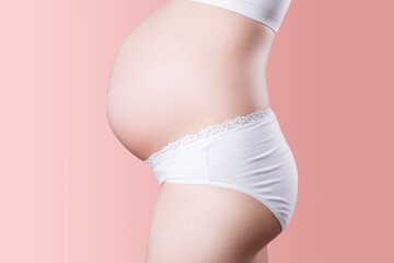 Pregnant woman in white panties on pink background
