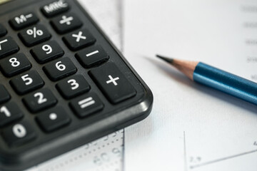 Calculator and pencil close-up on a blurred background.