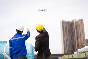 Professional Asian civil engineers using the unmanned aerial vehicle or UAV - drone for inspecting...