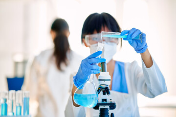 Female scientist making research pouring reagent into test tubes working in laboratory