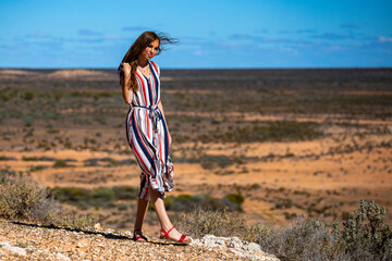 beautiful long-haired girl stands on top of a hill in the middle of nowhere in the desert in the...