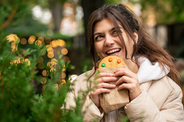 Attractive young woman with a beautiful gingerbread on a walk.