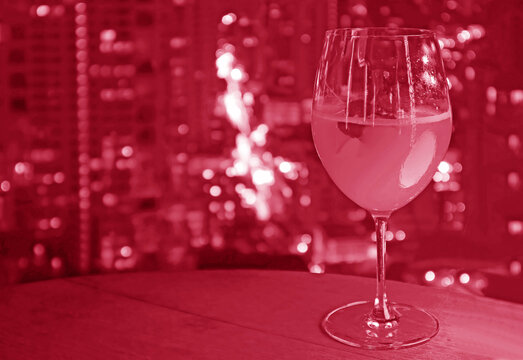 Pop art style hibiscus colored glass of cocktail with blurry aerial urban night view in background
