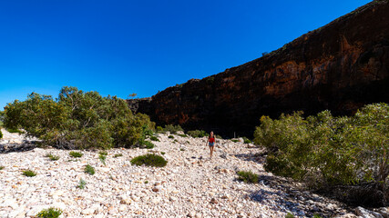 cute tanned girl in short shorts hiking through a gorge in cape range national park in western australia; hiking in the australian outback near exmouth