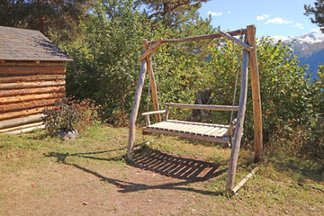 Fototapeta na wymiar Empty wooden swing beside the log cabin